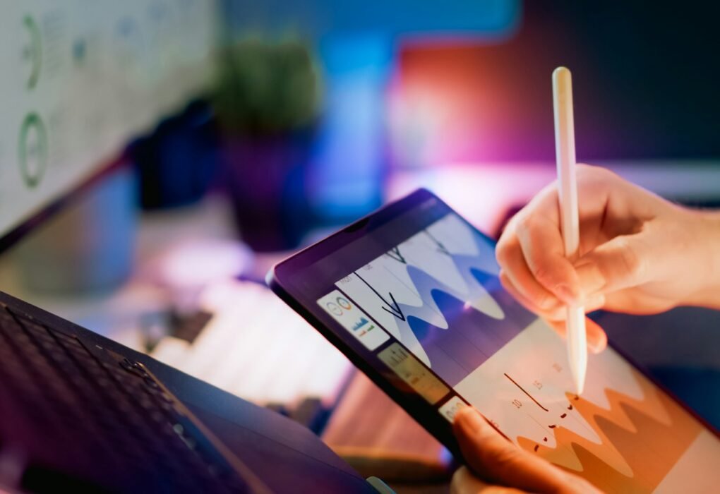 Person using stylus on tablet with charts